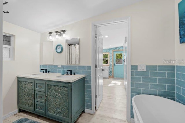 bathroom featuring a bathtub, vanity, wood-type flooring, and tile walls