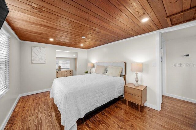 bedroom featuring hardwood / wood-style floors, wooden ceiling, and ornamental molding