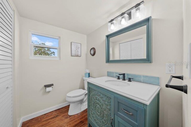 bathroom with hardwood / wood-style flooring, vanity, and toilet