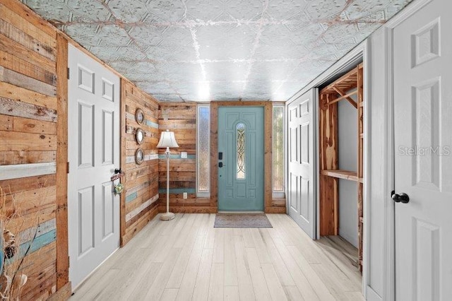 foyer with wood walls and light hardwood / wood-style floors