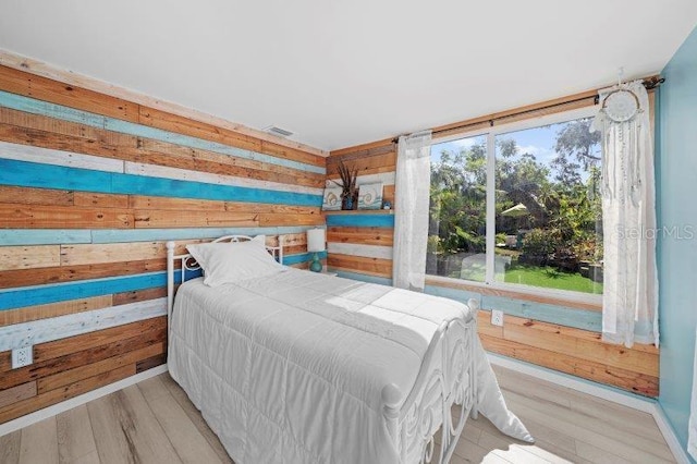 bedroom featuring wood walls and light hardwood / wood-style flooring