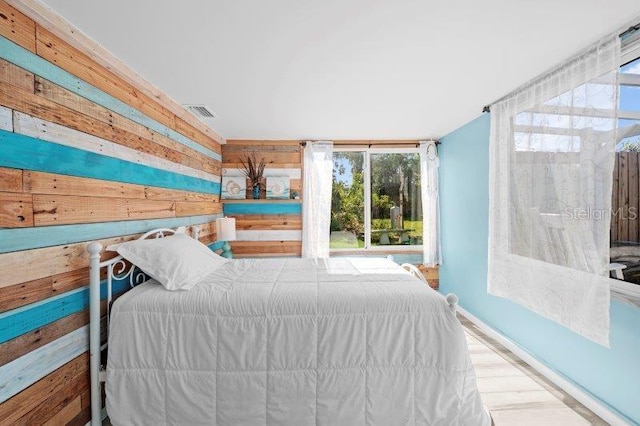 bedroom with wood walls and wood-type flooring