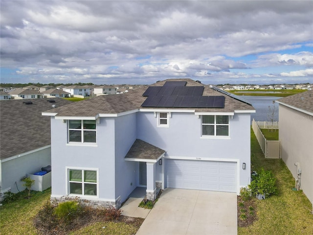 view of front of house featuring solar panels, a water view, and a garage