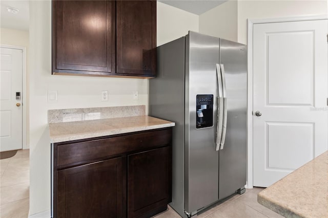 kitchen with dark brown cabinets, light tile patterned flooring, and stainless steel refrigerator with ice dispenser