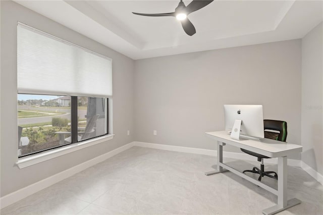 home office featuring a raised ceiling and ceiling fan