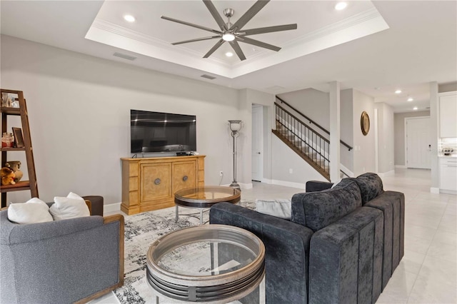 tiled living room featuring ceiling fan, ornamental molding, and a tray ceiling