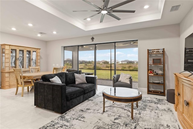 living room featuring ceiling fan, ornamental molding, and a tray ceiling