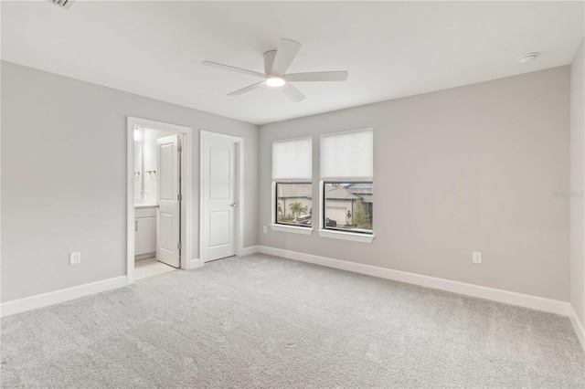 unfurnished bedroom with connected bathroom, ceiling fan, and light colored carpet