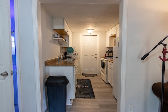 2029 Palm Ter, Sarasota, FL 34231 - kitchen with white appliances, light wood finished floors, white cabinets, and dark countertops