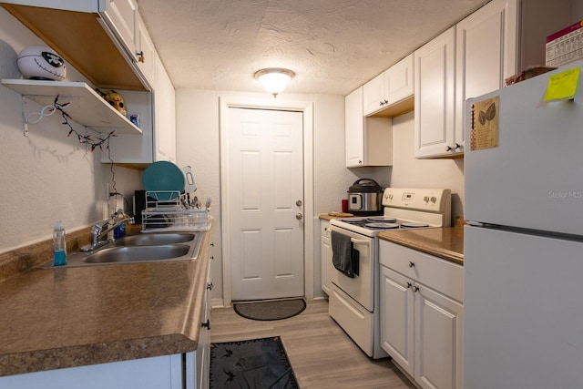 kitchen featuring white appliances, light hardwood / wood-style floors, white cabinetry, and sink