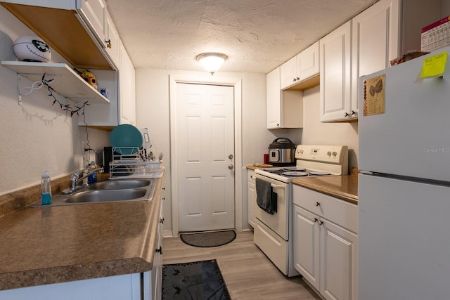 2029 Palm Ter, Sarasota, FL 34231 - kitchen with white appliances, open shelves, light wood-style flooring, white cabinets, and a textured ceiling