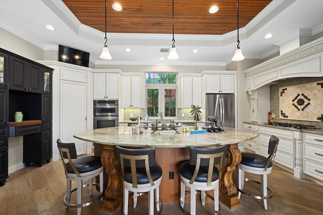 kitchen featuring crown molding, dark hardwood / wood-style flooring, a large island with sink, and appliances with stainless steel finishes