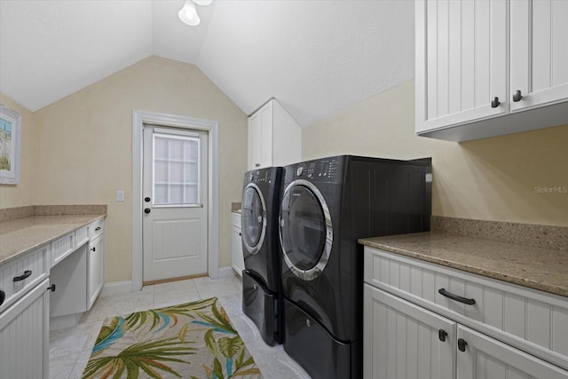 clothes washing area with washer and dryer, light tile patterned floors, and cabinets