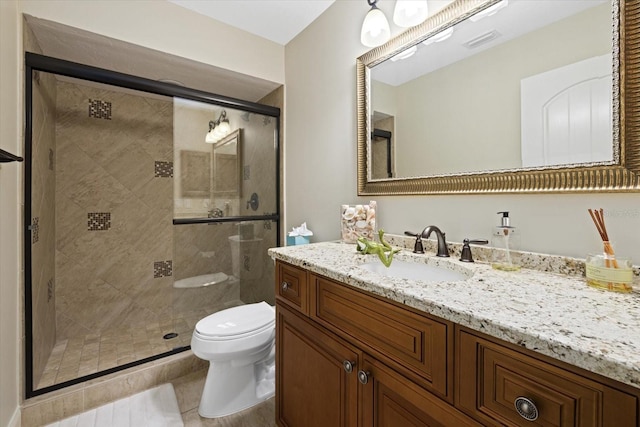 bathroom with tile patterned flooring, vanity, a shower with shower door, and toilet