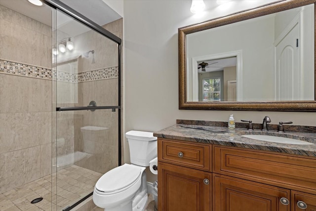 bathroom with ceiling fan, toilet, a shower with door, and vanity