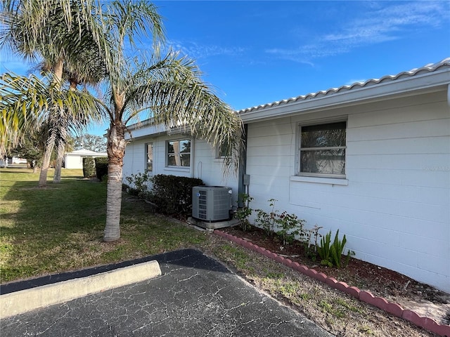 view of side of property with cooling unit and a lawn