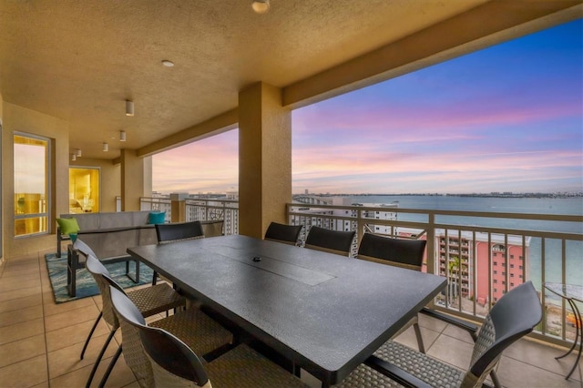 patio terrace at dusk featuring a balcony and a water view