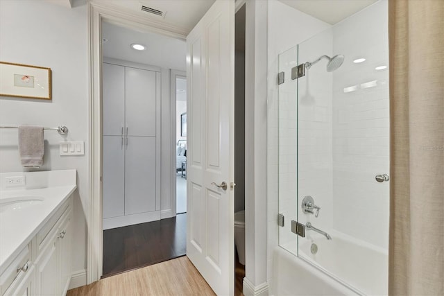 full bathroom with hardwood / wood-style floors, tiled shower / bath combo, toilet, and vanity