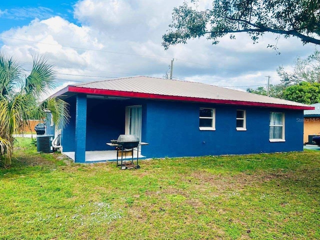 back of house featuring a lawn, a patio area, and central AC