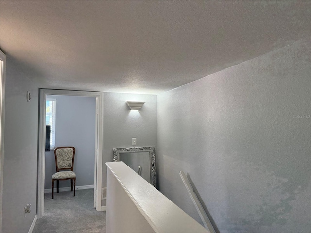 hallway with a textured ceiling and carpet floors