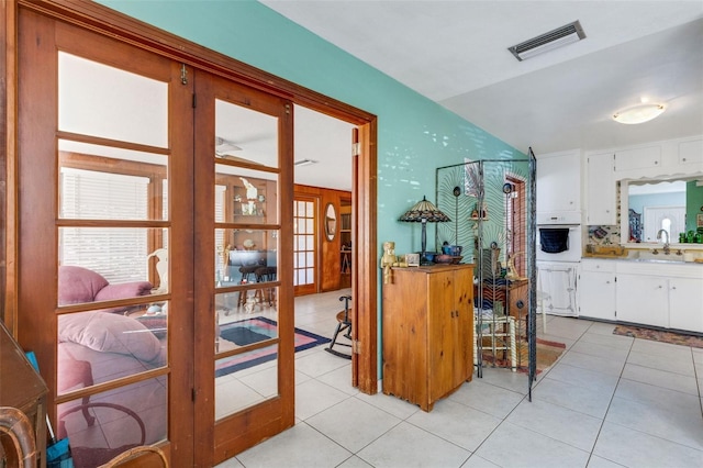 interior space with white cabinets, french doors, light tile patterned floors, and white oven