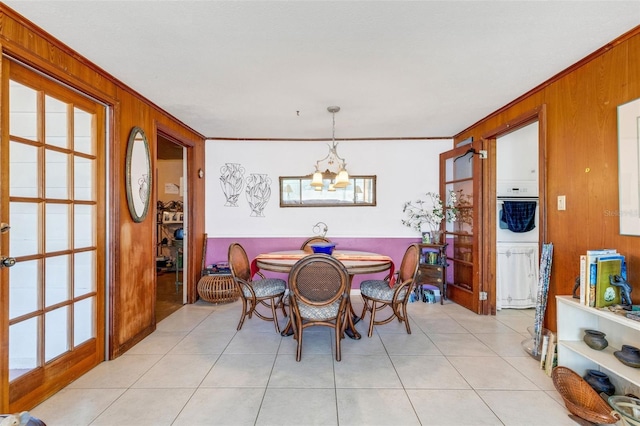 dining room featuring wood walls, crown molding, a notable chandelier, and light tile patterned flooring