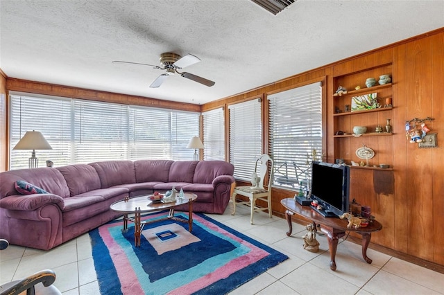 living room with a textured ceiling, light tile patterned floors, built in features, and wood walls