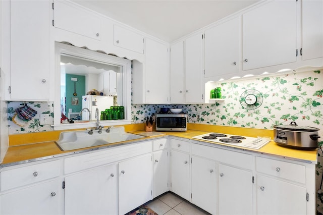 kitchen with sink, white cabinetry, light tile patterned floors, and white electric cooktop