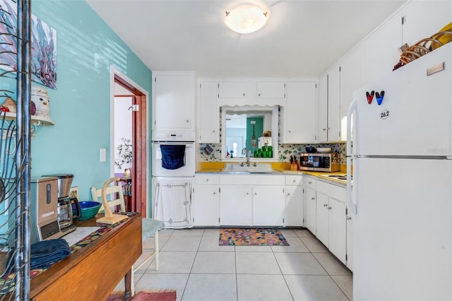 kitchen featuring sink, white cabinetry, white appliances, and light tile patterned floors