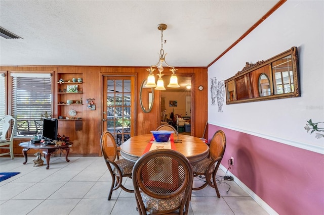 tiled dining area with built in features, wooden walls, a textured ceiling, and crown molding