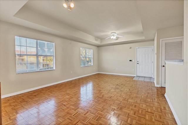 spare room featuring a tray ceiling, ceiling fan, and light parquet floors