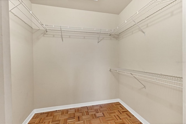 walk in closet with light parquet floors