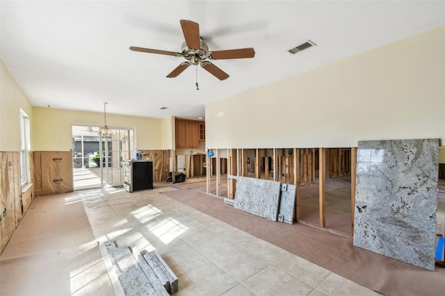 tiled spare room featuring ceiling fan with notable chandelier