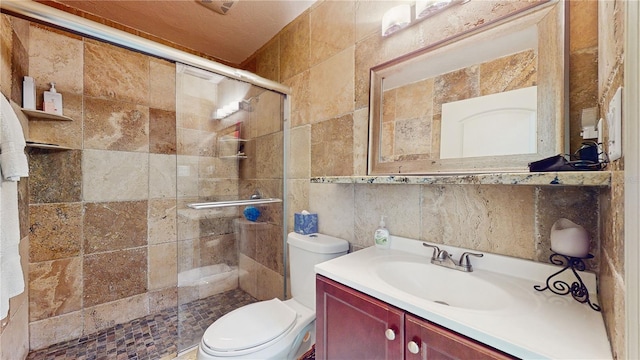 bathroom with an enclosed shower, vanity, toilet, and tile walls