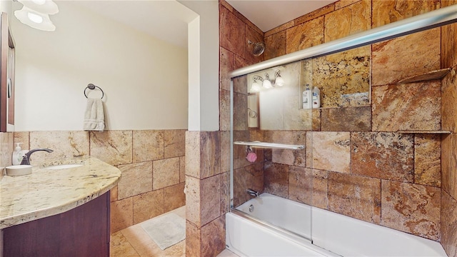 bathroom with vanity, enclosed tub / shower combo, and tile walls