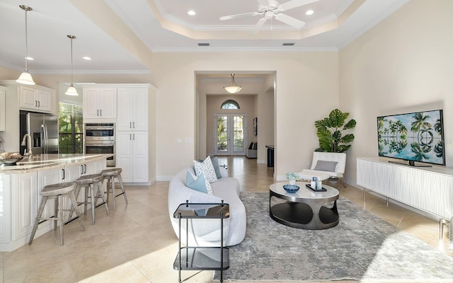 living room featuring ceiling fan, ornamental molding, and a tray ceiling