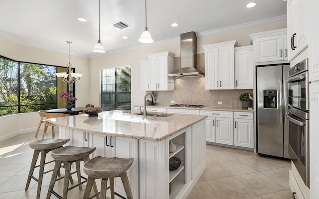 kitchen featuring pendant lighting, white cabinetry, a kitchen island with sink, and wall chimney range hood