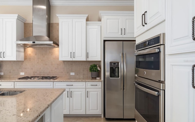 kitchen with white cabinets, stainless steel appliances, light stone counters, and wall chimney range hood