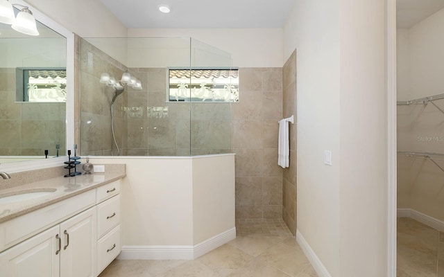 bathroom featuring a tile shower, vanity, and tile patterned floors