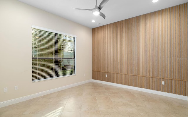 empty room featuring wood walls and ceiling fan