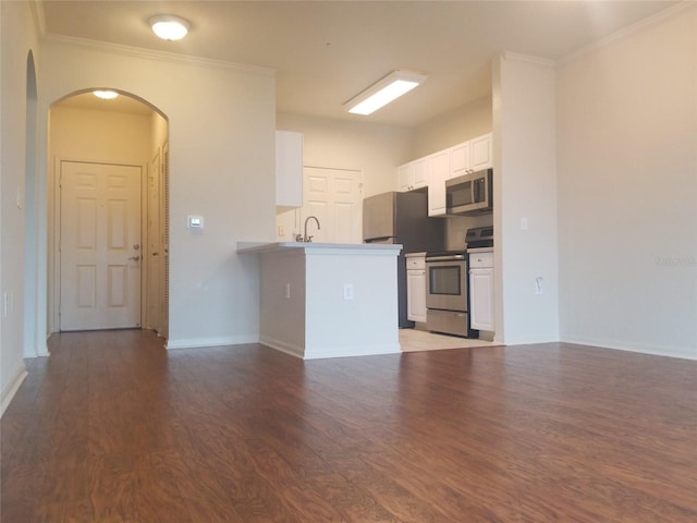 kitchen featuring dark wood-type flooring, kitchen peninsula, appliances with stainless steel finishes, white cabinets, and ornamental molding