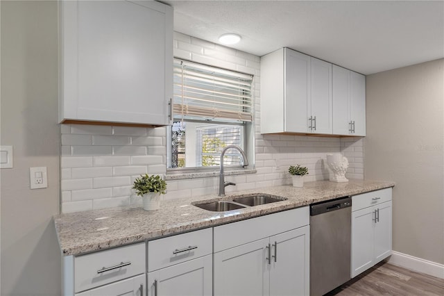 kitchen with dishwasher, white cabinetry, sink, and tasteful backsplash