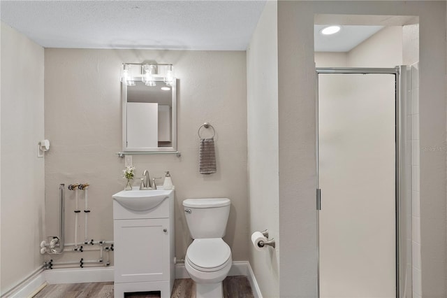 bathroom with vanity, a shower with door, wood-type flooring, and a textured ceiling