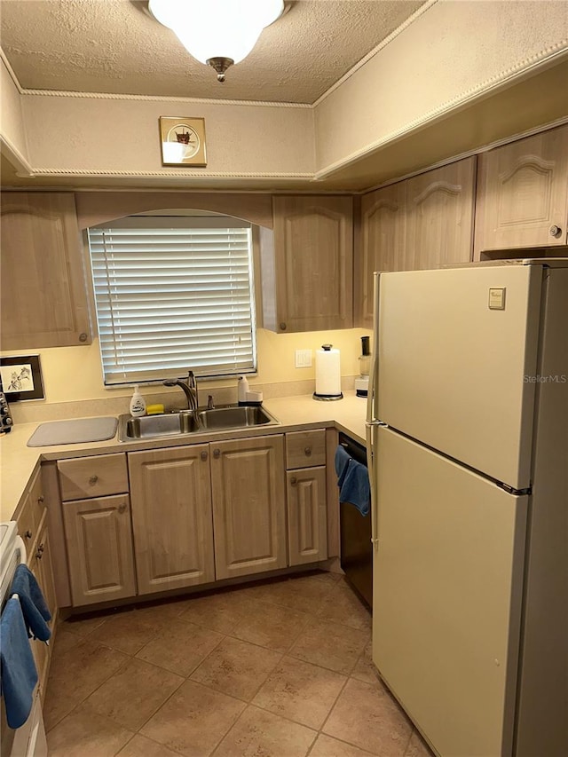 kitchen with sink, light brown cabinets, a textured ceiling, white appliances, and light tile patterned floors