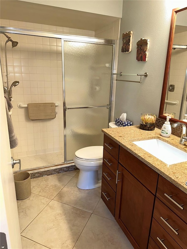 bathroom featuring toilet, vanity, tile patterned floors, and a shower with door