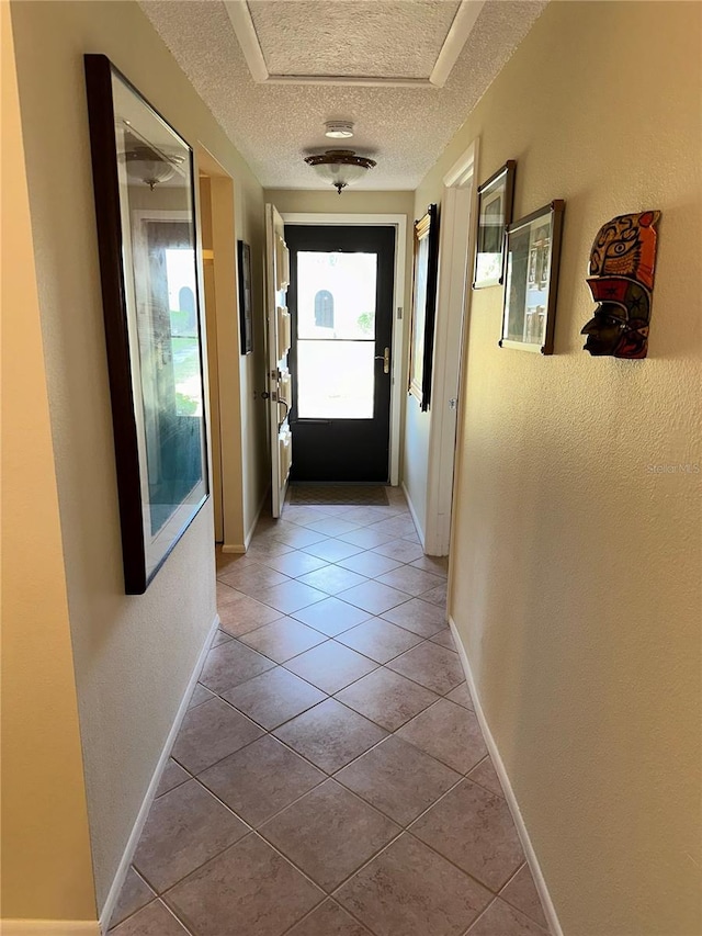 doorway to outside featuring a textured ceiling and light tile patterned flooring