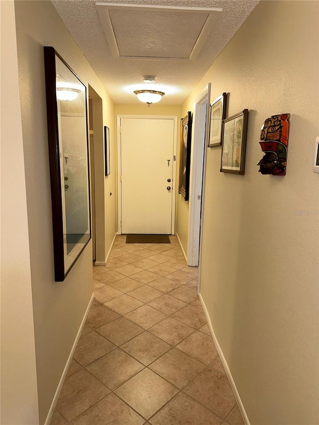 hall featuring a textured ceiling and light tile patterned flooring