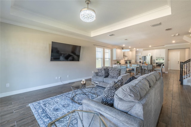 living room with dark hardwood / wood-style flooring, a raised ceiling, and crown molding