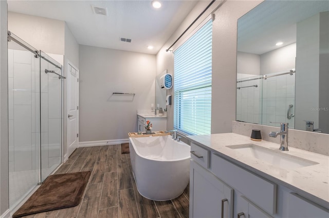 bathroom with hardwood / wood-style floors, vanity, and independent shower and bath