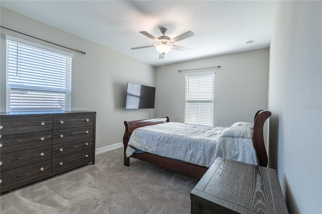 carpeted bedroom featuring ceiling fan and a textured ceiling